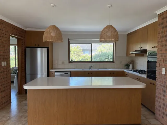 Two woven pendant lights above a kitchen island in a brick and timber home interior in Glendale